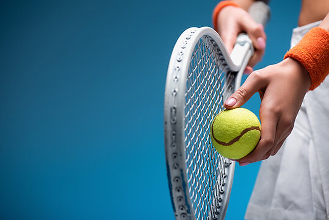 Hands holding a tennis racket and ball, ready to serve